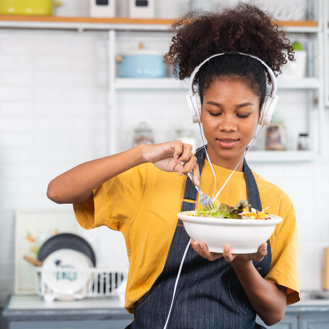 A woman eats a salad in her kitchen